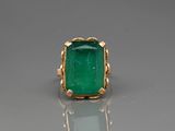 a close up of a ring with a green stone in it