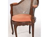 une chaise à l'ancienne, avec un dossier en rotin et une assise rembourrée de couleur orange