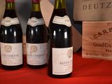 several bottles of wine are lined up on a red table cloth