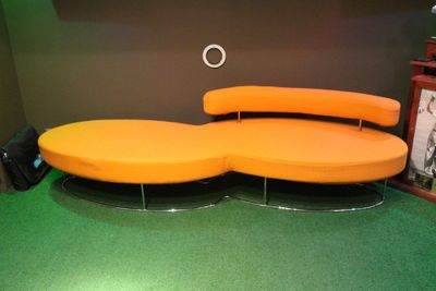 un canapé orange posé sur un sol vert dans une pièce