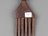 a wooden comb with a tag on it on a gray surface
