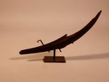a small wooden boat on a stand on a white surface