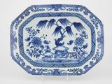 assiette bleue et blanche décorée d'oiseaux et de fleurs, posée sur un socle