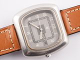 a silver watch with brown leather straps on a white surface