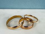 three gold wedding rings sitting on top of a white table