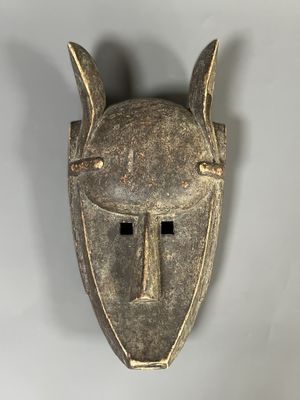 un gros plan d'un masque en bois accroché au mur