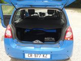 a blue car with its trunk open on a gravel road