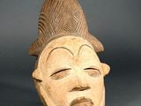 a close up of a wooden mask on a gray surface