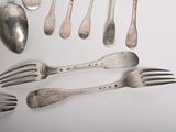 a lot of silver spoons and forks laid out on a table
