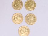 quatre pièces d'or sont disposées en ligne sur une surface blanche