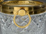 a glass ice bucket with a gold handle on a table