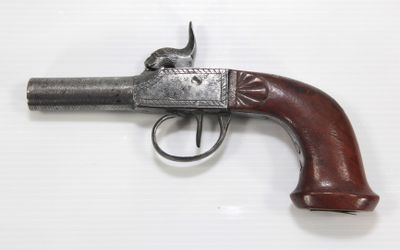 gros plan d'un pistolet avec un manche en bois sur une surface blanche