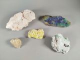 several different colored rocks on a white surface with a gray background