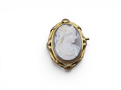 une broche en camée, dorée et blanche, représentant une femme de profil
