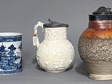 trois vases et une tasse posés les uns à côté des autres sur une table