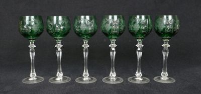 six verres à vin verts alignés sur un fond noir
