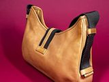 a close up of a brown purse on a pink surface
