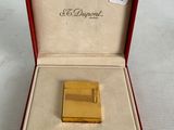 a gold lighter in a red box on a white surface