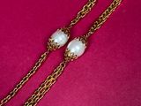 a close up of a necklace with pearls on a pink background
