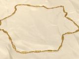 a close up of a gold necklace on a white cloth