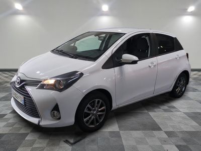 the white toyota yaris is parked in a large room