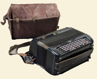a black accordion sitting next to a brown bag