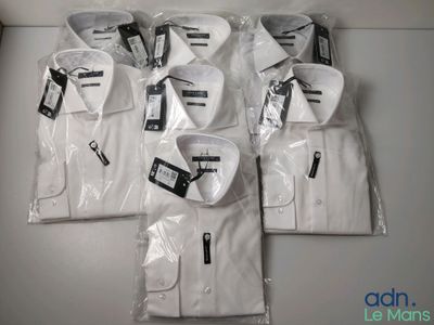 six men ' s white dress shirts in plastic bags on a table