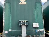 a green semi truck parked in a parking lot next to other semi trucks