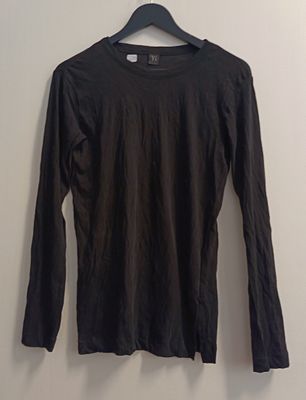 black long sleeved shirt hanging on a hanger against a white wall