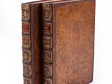 two old books sitting on top of each other on a white surface