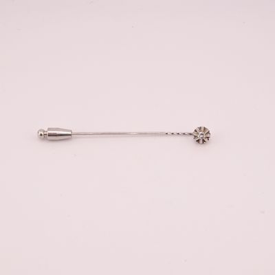a silver pin with a flower on it sitting on a white surface