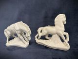 pair of white ceramic horse figurines on a black background