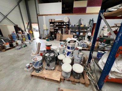 many buckets of paint sitting on a pallet in a warehouse