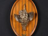 a wooden plaque with a bird on it on a wall