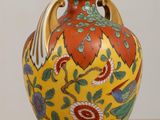 un vase jaune orné d'un motif rouge et vert