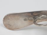 an antique silver spoon with a ring on it sitting on a white surface