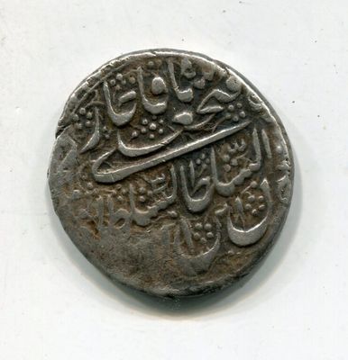 une vieille pièce d'argent portant une inscription en arabe sur un fond blanc