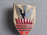 un gros plan sur un insigne rouge et doré orné d'un oiseau