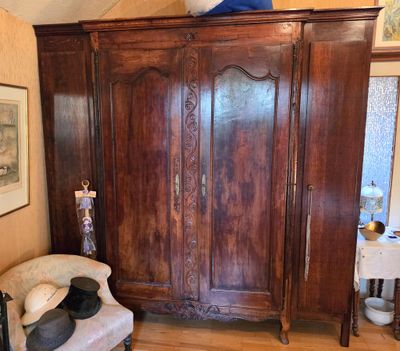 une chaise dans un coin d'une pièce où se trouve une grande armoire en bois