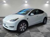 La Tesla Model Y blanche est garée dans une pièce dont le sol est à carreaux.