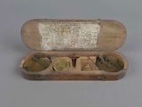 a small wooden box with three brass coins in it