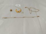 a close up of a white sheet with gold jewelry on it