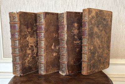 trois vieux livres posés sur une chaise en bois près d'un mur