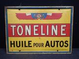 une vieille enseigne en tôle publicisant le produit « Toneline Hue pour autos » sur fond noir
