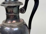 a silver tea pot with a black handle on a white background
