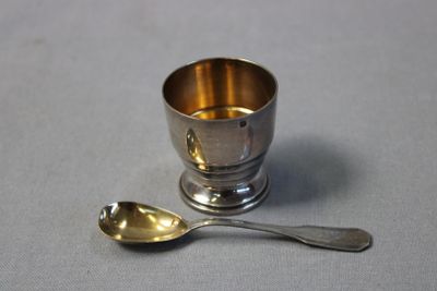 a silver cup and a spoon on a table