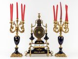three candles and a clock sitting on a table