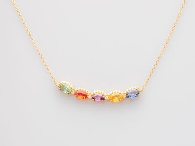 a gold necklace with multi colored stones on a white background