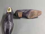 pair of men ' s shoes on a grey surface with a wooden heel