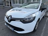 La voiture blanche est garée devant un immeuble sur lequel est accrochée une pancarte.